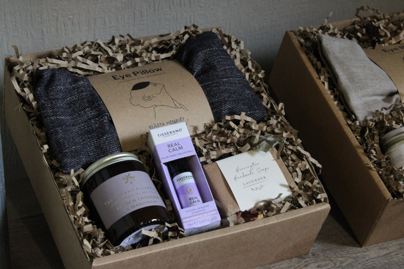 A gift box containing an eye pillow, lavender candle, Real Calm tea, soap, and shredded paper filler.
