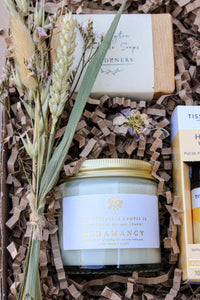 The Gardeners Delight Gift Box by Wild About Flowers contains a dried flower bouquet, rustic soap bar, "The Botanical Candle Co. Rêverie" soy wax candle, and essential oil in eco-friendly shredded paper.