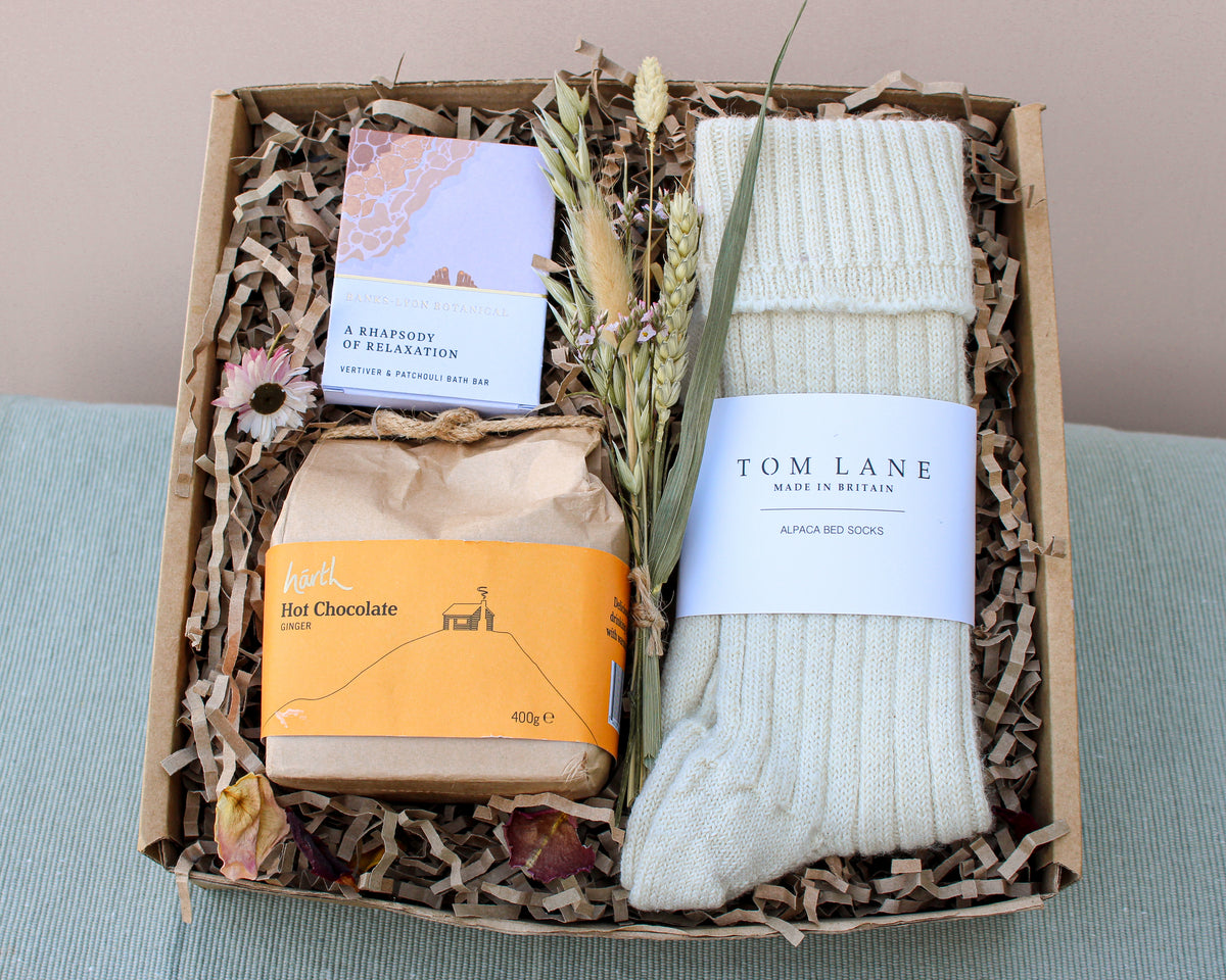 Wild About Flowers' Cosy Night In Gift Box offers "A Rhapsody of Relaxation" soap, Swiss-style hot chocolate mix, dried flowers, and alpaca bed socks, all elegantly arranged on shredded paper.