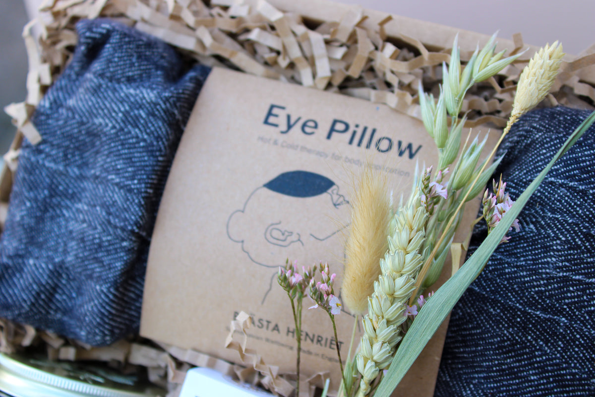 A close-up of Wild About Flowers' Lavender Relax Gift Box displays a boxed fabric eye pillow labeled "Eye Pillow" with a line drawing of its use; dried grasses and flowers decorate the packaging.