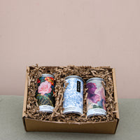 Wild About Flowers presents the Premium Wine Gift Set, a trio of award-winning wines in artistically designed cans. They're nestled in crinkle paper within a cardboard gift box, all set against a soft neutral textured background for an eco-friendly touch.