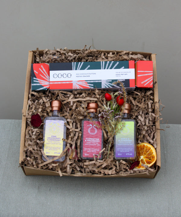 The Crackers about Gin Gift Box by Wild About Flowers includes two small bottles from Chew Valley Distillery, paired with a box of chocolate buttons. It is beautifully decorated with dried orange slices and flowers, all nestled in shredded paper, making it an ideal Christmas gift.