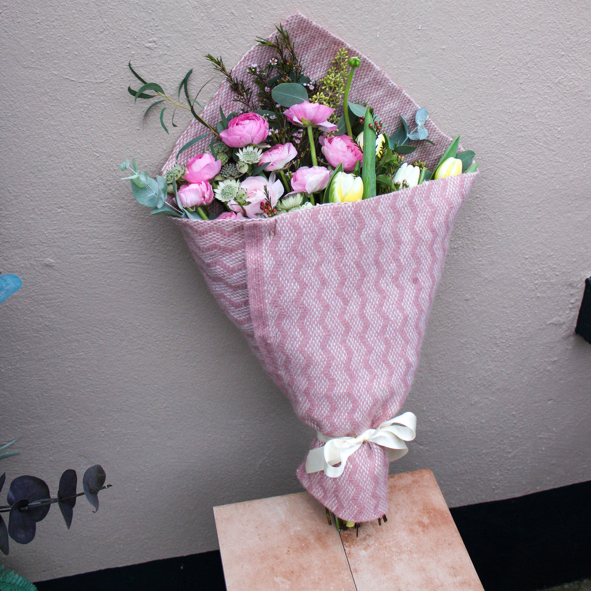 The 'Armful of Love' Valentines wrap from Wild About Flowers features pink, white, and yellow blooms in textured pink cloth with a white ribbon—an ideal romantic gift for fresh flower delivery.