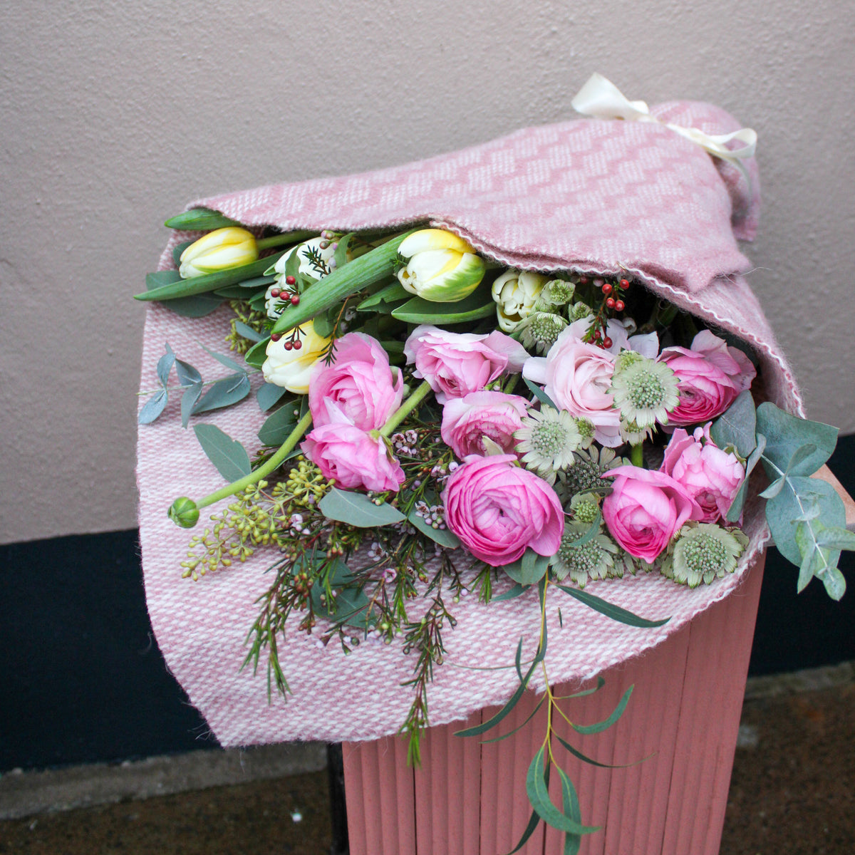 The 'Armful of Love' Valentines wrap by Wild About Flowers features pink and white roses and tulips in textured pink cloth, making it the perfect romantic bouquet for Valentine’s Day.
