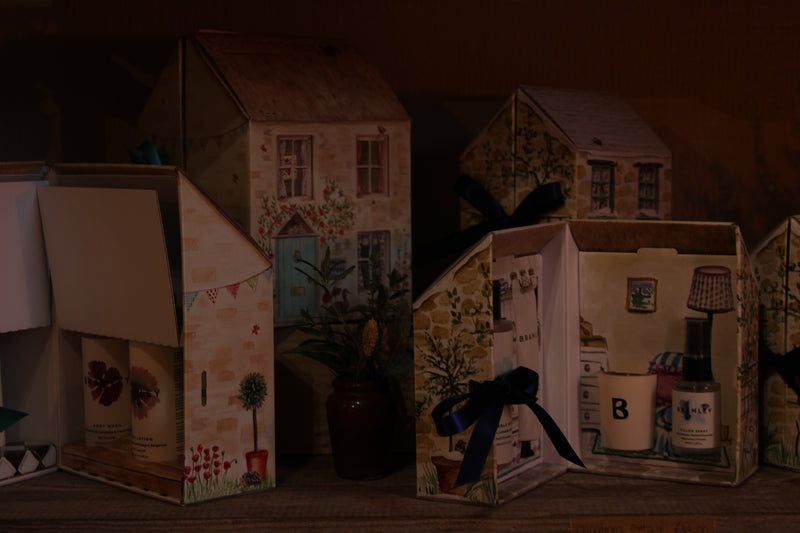 Decorative paper houses with various items on a wooden surface
