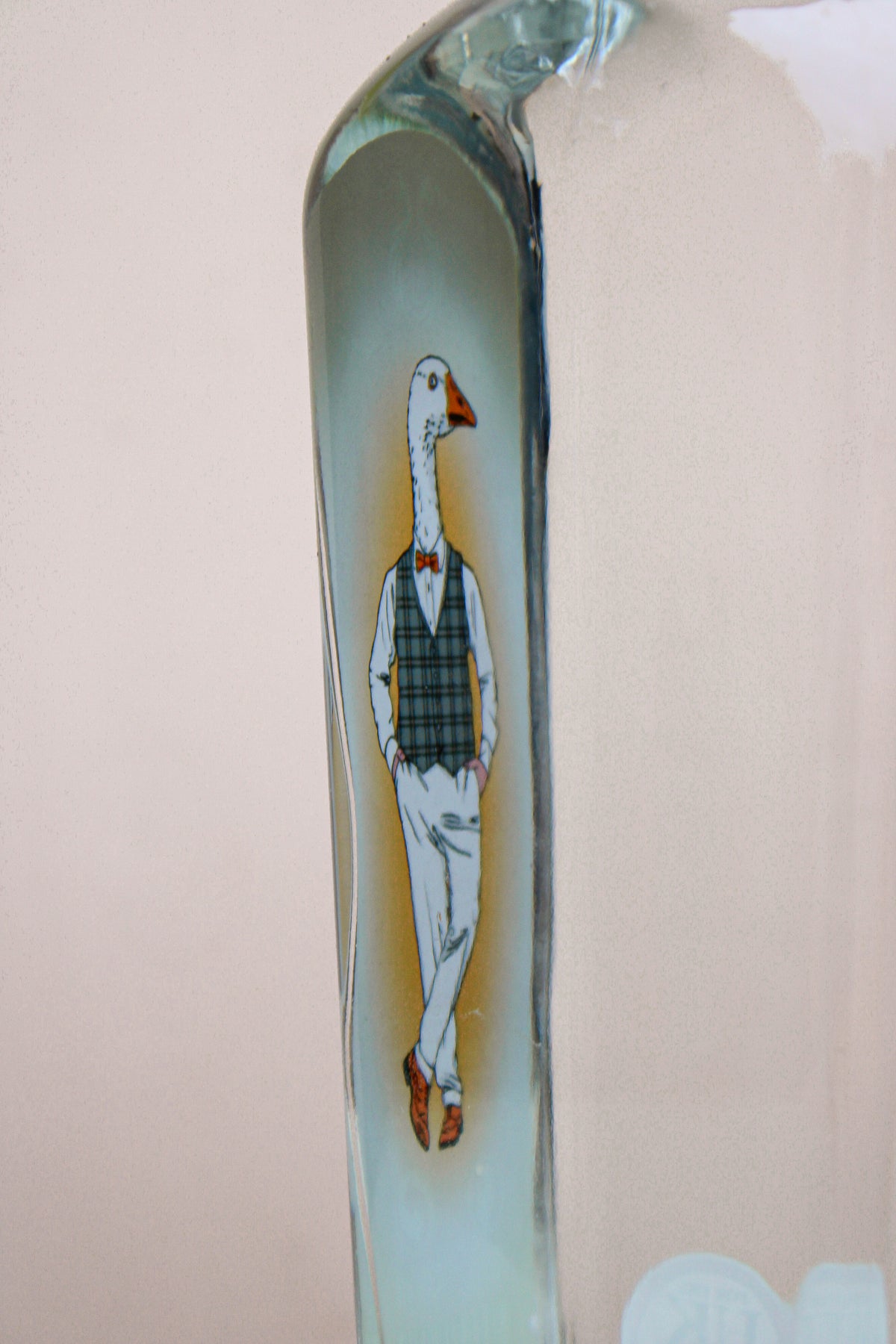 Illustration of a suited goose wearing a plaid vest, bow tie, and shoes inside a clear tall glass bottle of award-winning Wild About Flowers Chew Valley Gin, standing upright with a relaxed posture.