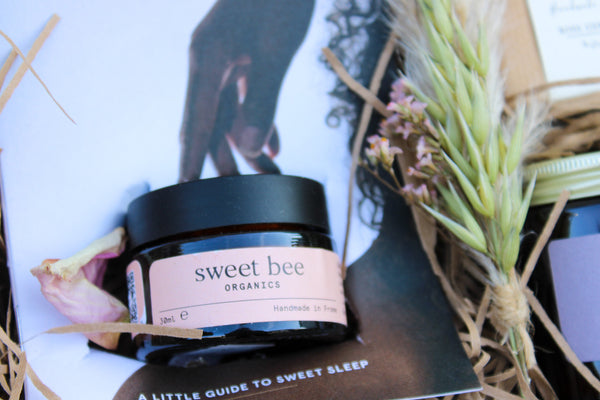 The Wild About Flowers Mother's Day Gift Box includes a Sweet Bee ORGANICS jar and magnesium butter nestled in a box with dried flowers and straw. A booklet titled "A LITTLE GUIDE TO SWEET SLEEP" adds an extra touch, making it the perfect gift idea.