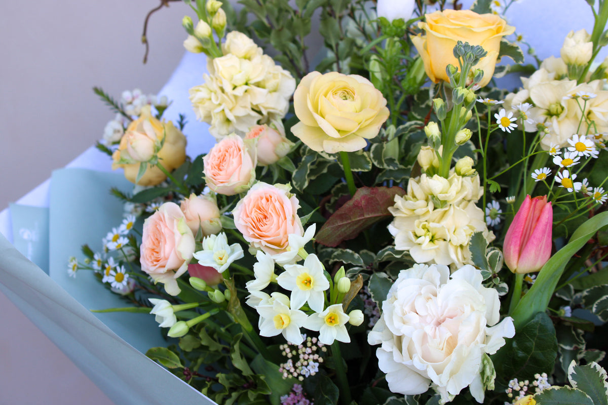 Surprise your mom this Mother's Day with the "Wild Thing" by Wild About Flowers, a hand-tied design featuring yellow roses, peach and white blooms, daisies, and greenery in light blue paper. Ideal for delivery in Bristol and Bath.