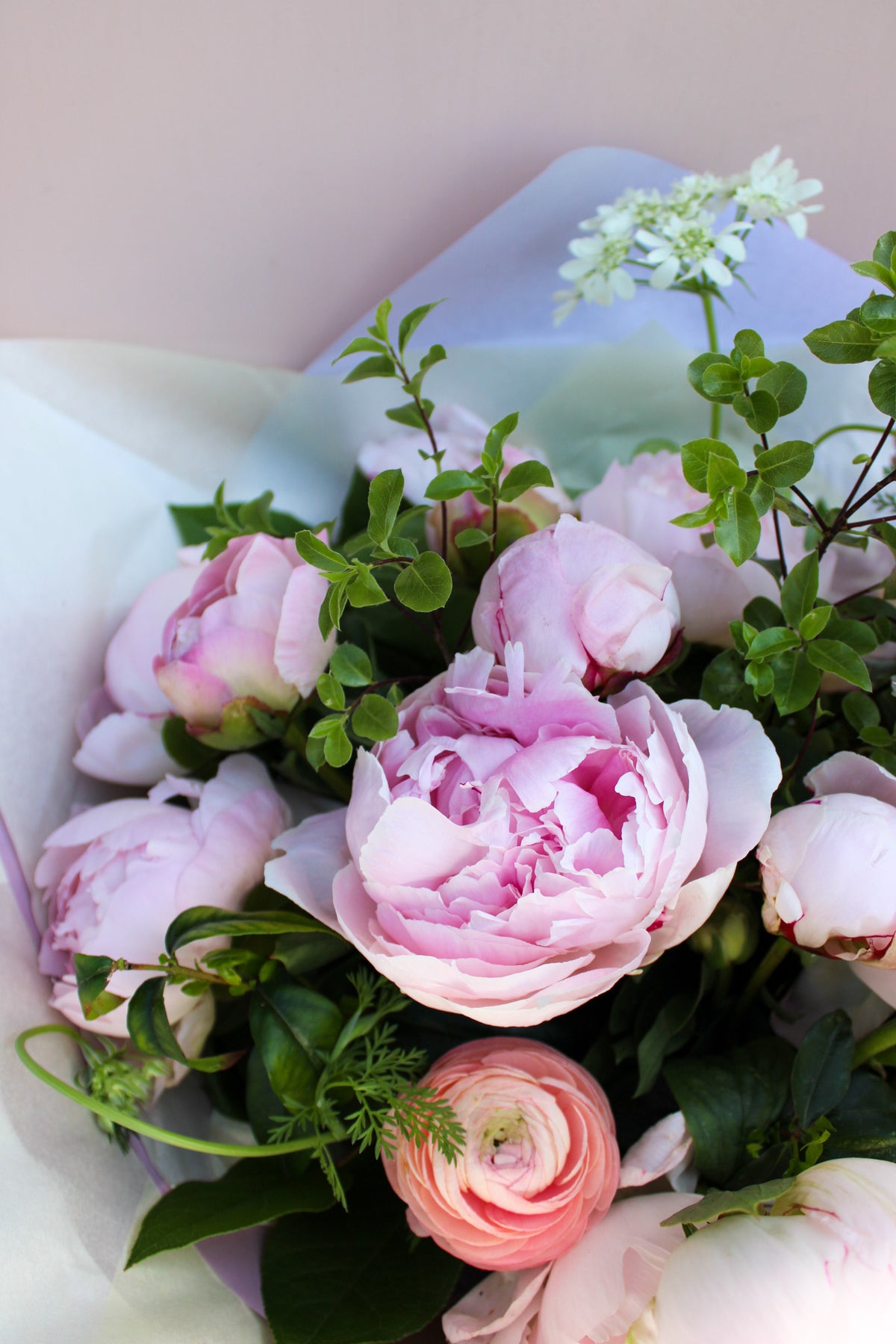 The Peony Love Hand Tied by Wild About Flowers features premium peonies and ranunculus with lush greenery and delicate white blooms, artfully arranged for a timeless floral gift.