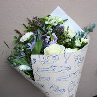 Bouquet of flowers wrapped in paper with blue line drawings on a neutral background