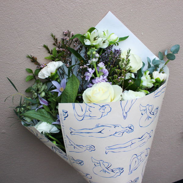 Bouquet of flowers wrapped in paper with blue line drawings on a neutral background