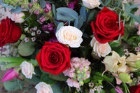 The Valentine's Day Blooms by Wild About Flowers is a vibrant bouquet of red and white roses with green leaves, pink flowers, and small white blossoms—an elegant gift for Valentine's Day.