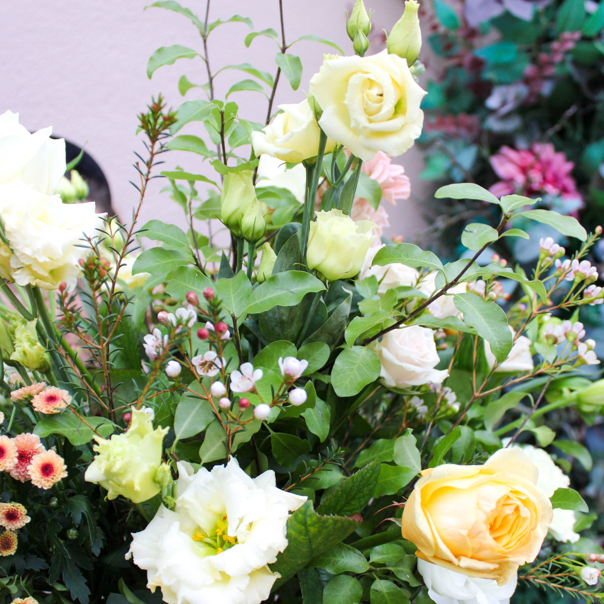The 'Jar of Joy' Vase Arrangement by Wild About Flowers features pastel roses, white blossoms, green leaves, and pink accents, artfully arranged—an ideal Valentine’s Day flower gift.