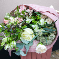 The ‘Strawberry Kisses’ Valentine’s Flower Wrap by Wild About Flowers features white and pale pink roses with greenery, artfully wrapped in soft pink fabric—perfect for a romantic bouquet or fresh flower delivery.