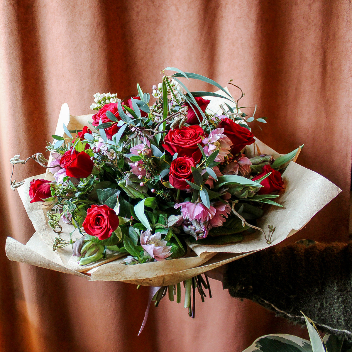 The 'True Romantic' Valentines Bouquet by Wild About Flowers features red naomi roses, pink blooms, and lush greenery in brown paper—perfect for gifting on Valentine's Day.