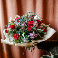 The 'True Romantic' Valentines Bouquet by Wild About Flowers features red naomi roses, pink blooms, and lush greenery in brown paper—perfect for gifting on Valentine's Day.