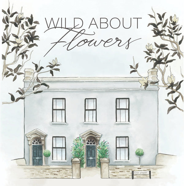 The Wild About Flowers Gift Card features a white two-story building with large windows, greenery, and blooms at the entrance. "Wild About Flowers" is framed by tree branches above, and a High Street sign completes the charming scene.